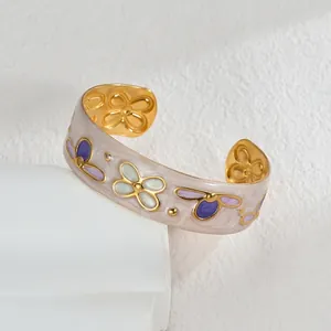 Detailed close-up of a floral enamel cuff bracelet with intricate embossed gold patterns