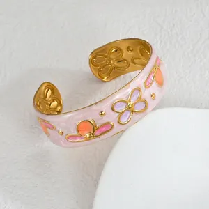 Macro shot of gold floral bangle with colorful enamel flowers and marble texture
