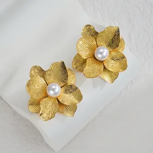 Elegante goldene Blumenohrringe mit gebürsteter Metallstruktur und Perle auf Stein