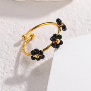 Detailansicht eines offenen goldenen Perlenrings mit drei schwarzen Blumenanhängern mit Goldkern