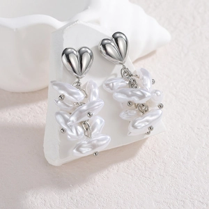 Vue détaillée des boucles d'oreilles cœur avec perles baroques sur support blanc