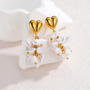 Détail de clous dorés en forme de cœur avec perles baroques suspendues sur support pierre