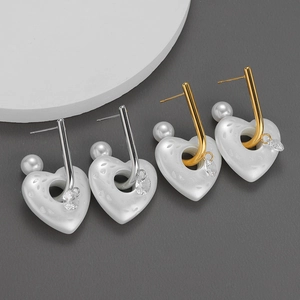 Orecchini a cuore in oro e argento con perle e zirconi su sfondo grigio professionale