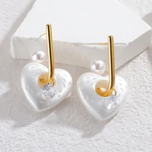 Dettaglio di orecchini a cuore traforato con perla bianca e goccia di cristallo