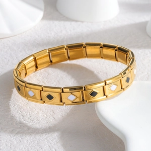 Dettaglio del bracciale a maglie dorate con motivo a rombi bianchi e neri sulle maglie