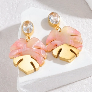 Macro detail of monstera leaf earrings with pink marble resin and golden metal texture