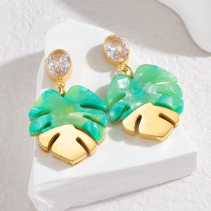 Macro detail of tropical monstera leaf earrings with green acrylic and gold metal finish