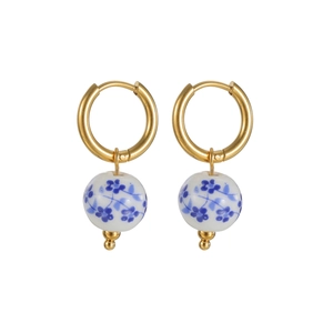 Detail of gold hoop earrings with blue and white floral porcelain bead charms