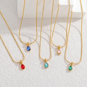 Detail of teardrop zircon necklaces in five colors with golden snake chains on white stone
