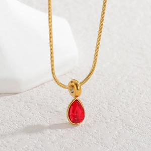 Macro shot of gold teardrop necklace with red zircon stone and sleek snake chain