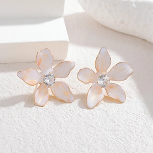 Detailed close-up of white enamel flower earrings with gold edges and zircon centers