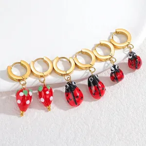 Boucles d'oreilles dorées avec pendentifs fraise et coccinelle en émail coloré, vue de groupe