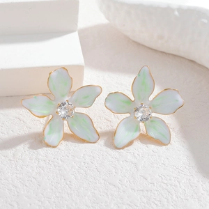 Macro shot of floral earrings with white enamel petals, gold edges and center zircon
