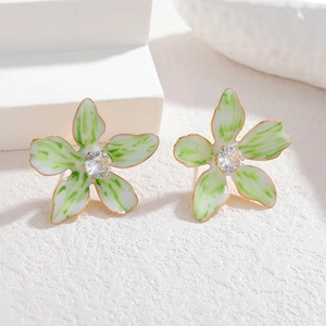 Macro shot of green and white enamel flower stud earrings with a sparkling zircon center