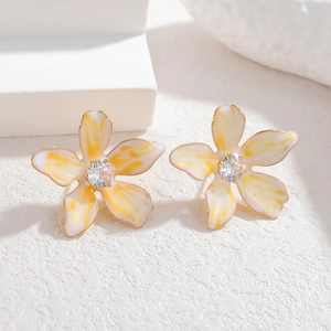 Close-up of enamel flower stud earrings with gold edges and central diamond detail