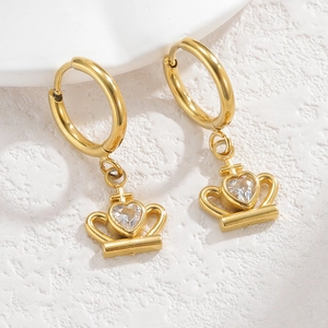 Close-up of 18K gold crown earrings with heart-shaped cubic zirconia on a white stone