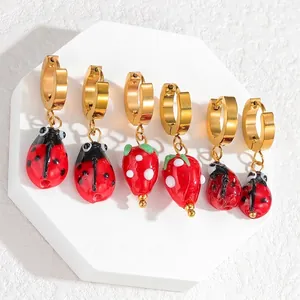 Lot de trois paires de boucles d'oreilles dorées avec fraises et coccinelles en émail