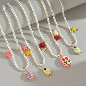 Vue détaillée des colliers de perles avec pendentifs tulipe et poisson sur un support blanc