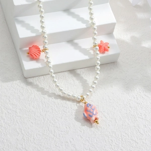Détail d'un collier de perles avec des breloques de coquillages et de poissons roses
