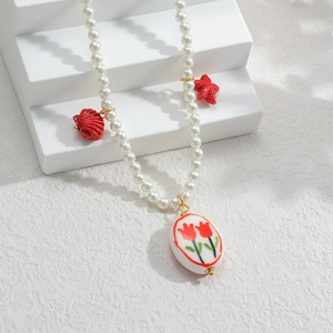 Détail du collier de perles avec pendentif tulipe en céramique et breloques étoile de mer