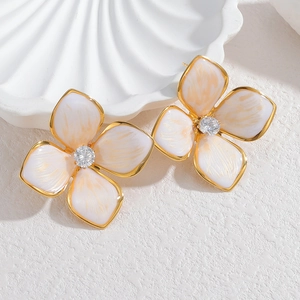 Vue détaillée des boucles d'oreilles fleur en émail blanc avec zircon central brillant