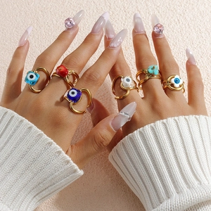 Bohemian gold Evil Eye ring set with turquoise and red beads on textured background