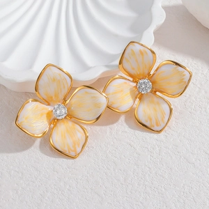 Détail macro de boucles d'oreilles fleurs en émail blanc avec pierre en zircon centrale