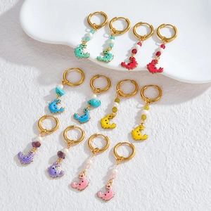 Detail view of colorful crab drop earrings with gold hoops, pearls, and enamel finish