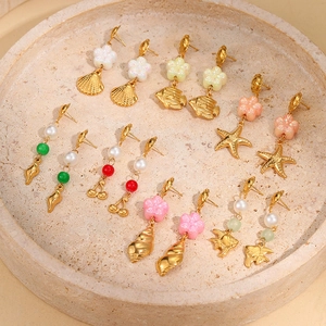 Gold ocean themed earring set with starfish, shells, and pearls on a stone tray