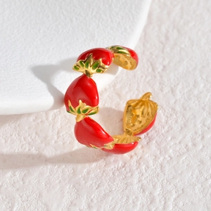 Macro shot of an adjustable gold ring featuring vibrant red strawberry enamel charms