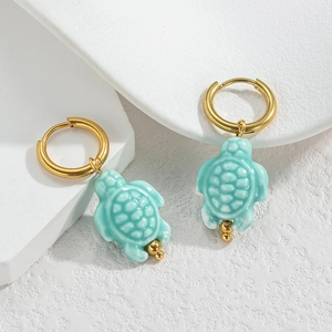 Vue détaillée des boucles d'oreilles tortue dorées avec coque en céramique bleue
