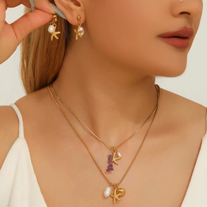 Golden ocean theme jewelry set with starfish pendants, pearls and shells on a model