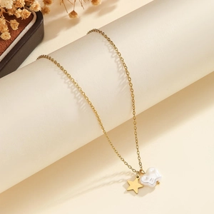 Close-up of golden necklace with star pendant and textured pearl charm on minimalist stand