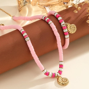 Gros plan du collier en perles Heishi roses et blanches avec pendentif coquillage doré