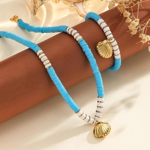 Vue détaillée des pendentifs coquillage dorés sur l'ensemble de bijoux en perles boho
