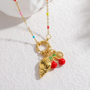 Detail of gold necklace with cherry pendant, conch shell charm and colorful beads