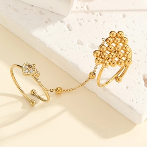 Detailed macro view of a vintage gold double-finger ring with heart charms and chains