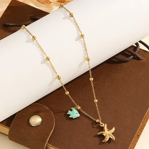 Close-up of golden beaded chain with green enamel fish and starfish sea charms