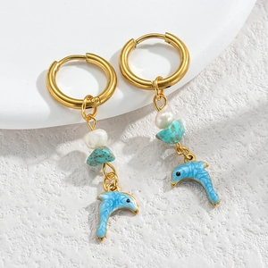 Detailed close-up of a gold dolphin earring with turquoise beads and baroque pearl