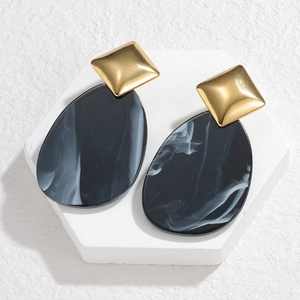 Macro detail of geometric acrylic resin earrings with black and white marble ink texture