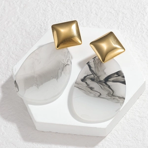 Detail of acrylic drop earrings showing gold square studs and ink marble texture