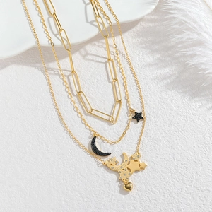 Three-layer gold necklace with star, crescent moon, and heart pendants on white stone