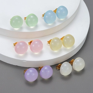 Set of six pairs of colorful translucent resin ball earrings with glitter on a white stand