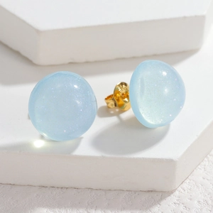 Detailed macro view of light blue round resin earrings with sparkling glitter texture