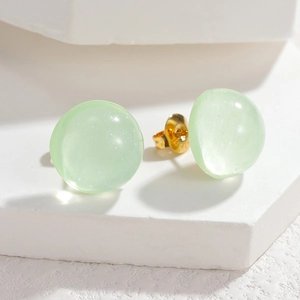 Macro shot of light green resin stud earrings with glitter finish and S925 gold-plated backs