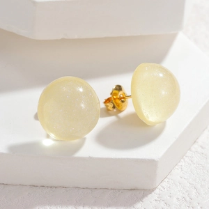Macro shot of semi-translucent pale yellow resin stud earrings with subtle gold shimmer