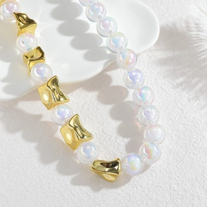 Collier de perles irisées terre avec intercalaires géométriques dorés sur fond blanc