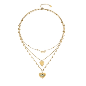 Collier doré à trois rangs avec pendentifs cœur et œil porte-bonheur sur fond blanc