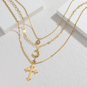 Detailed view of layered gold necklace with crescent moon and crystal cross pendants