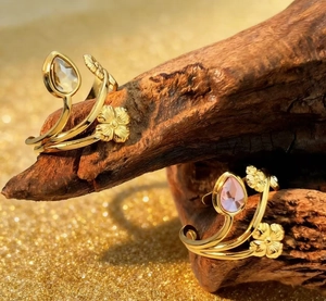 Detailed macro view of gold flower rings with pink and clear teardrop crystals on wood